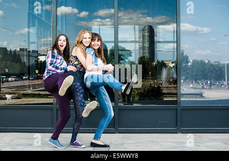 Three young women dancing on one leg in city Stock Photo