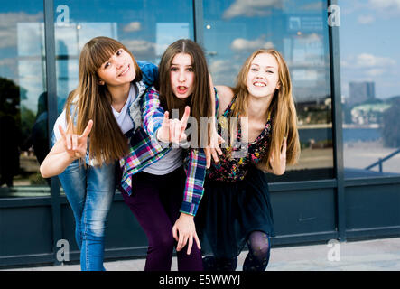 Three young women leaning forward in a row and making I love you hand gesture Stock Photo