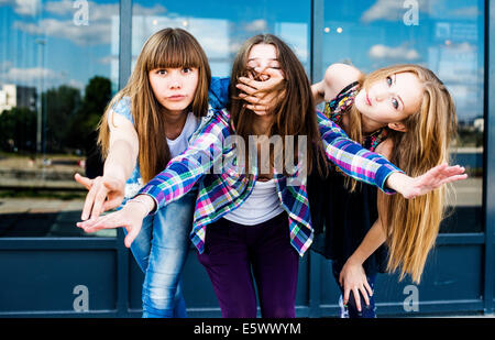 Three young women in a row leaning forward and covering mouth Stock Photo