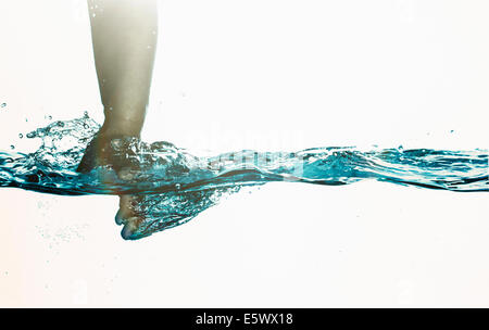 Surface level view of toddlers hand plunging into clear water Stock Photo