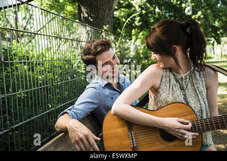 Young couple playing acoustic guitar in park Stock Photo