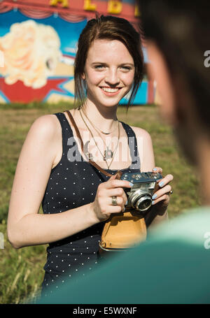 Young couple taking photographs on SLR camera at funfair Stock Photo