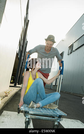Young couple fooling around on shopping cart in street Stock Photo