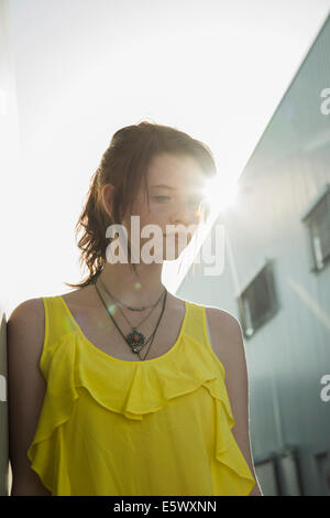 Young sullen girl in yellow blouse gazing down Stock Photo