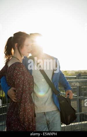 Romantic young couple leaning against fence on rooftop Stock Photo