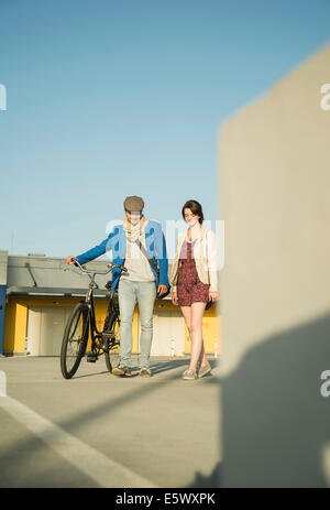 Young couple pushing bicycle along street Stock Photo