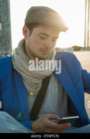 Young man leaning against wall texting on smartphone Stock Photo