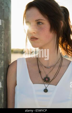 Close up portrait of serene young woman leaning against wall Stock Photo