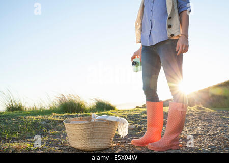 Young woman in wellies standing against sunset Stock Photo