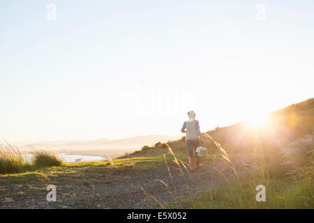 Young woman walking on hill at sunset Stock Photo