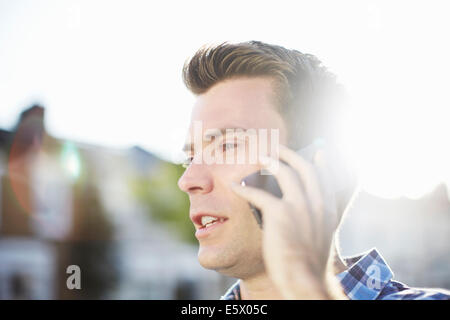 Mid adult man talking on smartphone on street Stock Photo