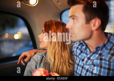 Couple looking out of city taxi window at night Stock Photo