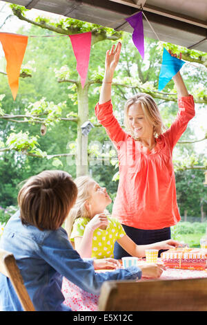 Mother chatting with children and putting up bunting Stock Photo