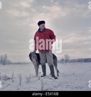 Portrait of man with deerhound in snow covered field Stock Photo