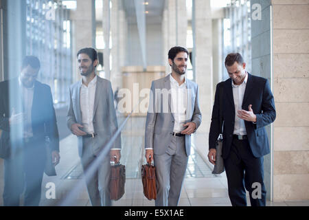 Two young businessmen walking and chatting in conference centre Stock Photo