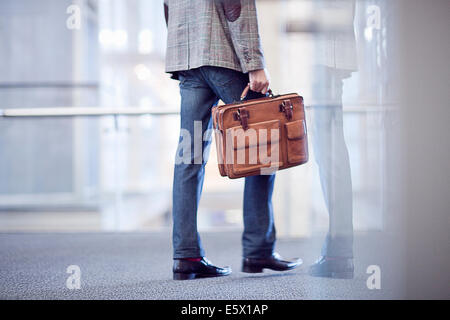 Cropped shot of young businessman with briefcase in conference centre Stock Photo