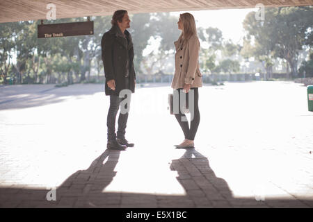 Young woman chatting to mid adult man in city underpass Stock Photo