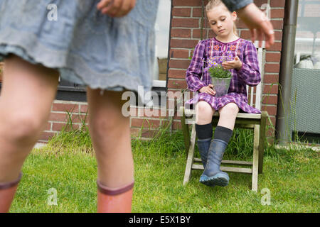 Girl on garden seat gazing at flower pot plant Stock Photo