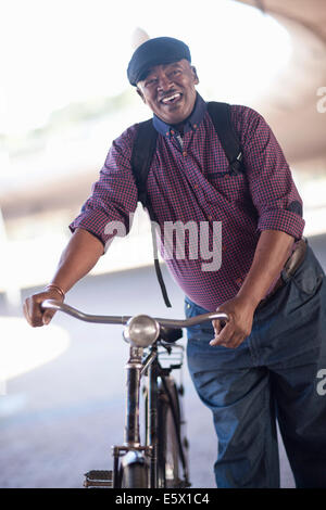 Senior man pushing bicycle through city underpass Stock Photo