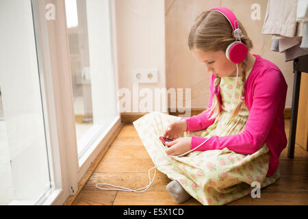 Girl sitting on floor selecting music for headphones