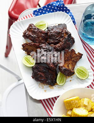 Plate of barbecued ribs with lime and corn cobs Stock Photo