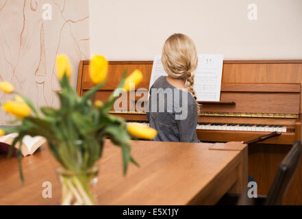 Rear view of girl at the piano in dining room Stock Photo