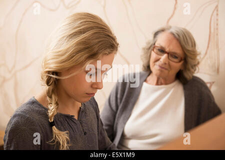 Girl playing the piano watched by grandmother Stock Photo