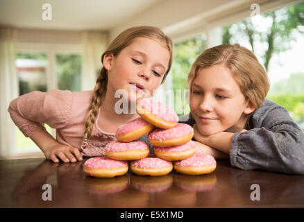 Two sisters gazing at stack of with doughnut holes on kitchen counter Stock Photo