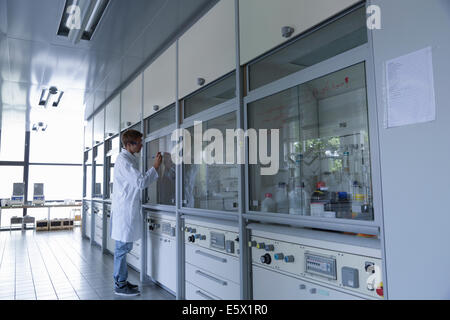 Young male scientist writing on fume cupboard window Stock Photo