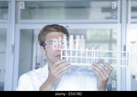 Young male scientist analyzing test tubes in lab Stock Photo
