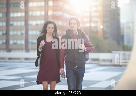 Couple walking across rooftop parking lot in city Stock Photo