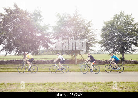 Cyclists riding on leafy countryside road, Cotswolds, UK