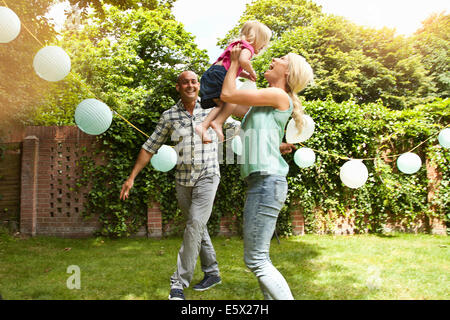 Happy couple playing with toddler daughter in garden