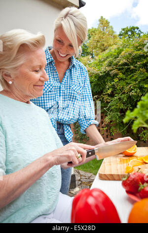 Grandmother and granddaughter chatting while preparing food at garden table Stock Photo