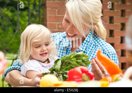 Mother and toddler daughter preparing food at garden table Stock Photo