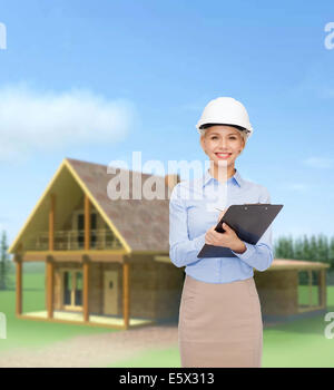smiling businesswoman in helmet with clipboard Stock Photo