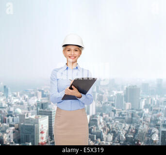smiling businesswoman in helmet with clipboard Stock Photo