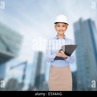 smiling businesswoman in helmet with clipboard Stock Photo