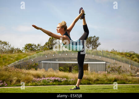 Woman practising yoga in park Stock Photo