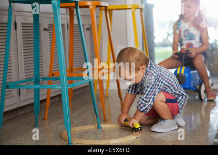 Male toddler and sister playing in kitchen Stock Photo