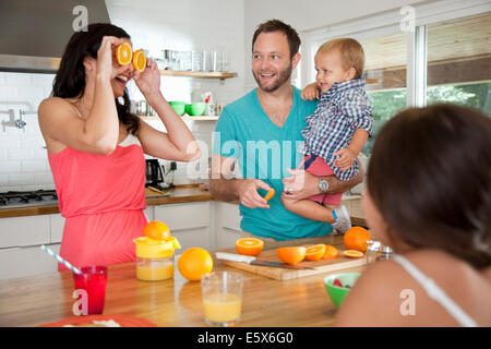 Mother making a face with oranges for her family at breakfast bar Stock Photo