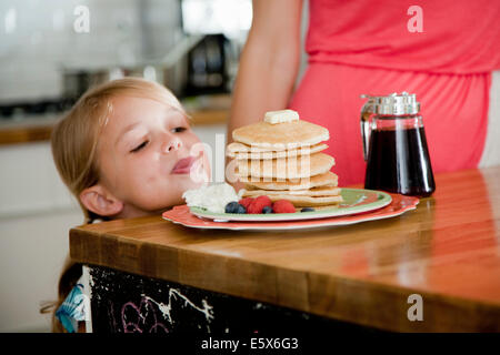 Mischievous girl gazing at pancakes on breakfast bar Stock Photo