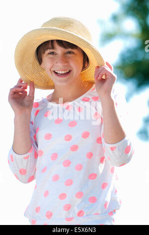 Portrait of ten year old girl holding onto straw hat Stock Photo