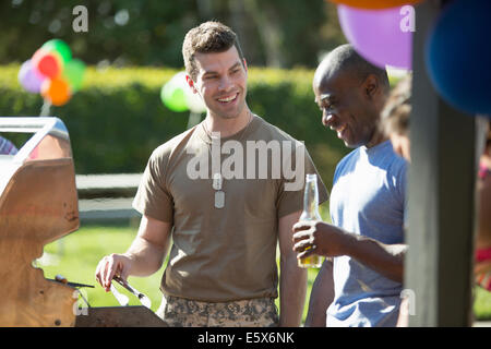 Male soldier barbecuing with friends at homecoming party Stock Photo