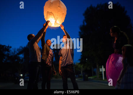 Friends holding up sky lantern to celebrate Stock Photo