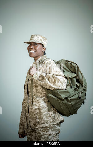 Side view studio portrait of confident female soldier with rucksack Stock Photo