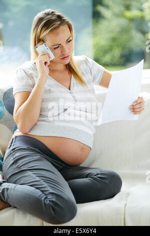 Pregnant woman looking at credit card statement Stock Photo