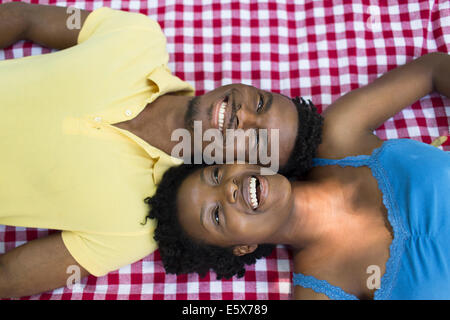 Overhead portrait of young couple lying on picnic blanket on opposite sides Stock Photo