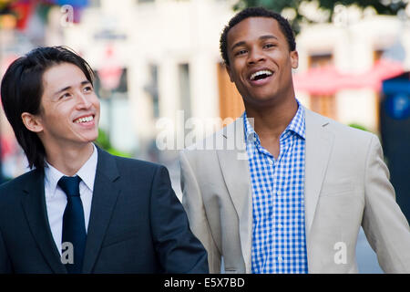 Two businessmen chatting and laughing on city street Stock Photo