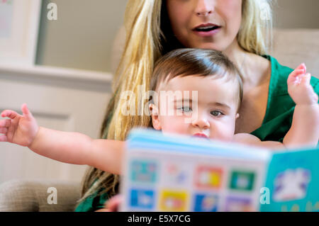 Mid adult mother reading picture book to baby daughter Stock Photo